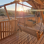 Veranda van de lodgetent met barbecue en schommel